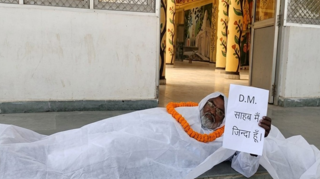 “साहब, मैं जिंदा हूं…” कफन ओढ़कर डीएम ऑफिस के बाहर लेट गया शख्स, सिस्टम पर उठे सवाल